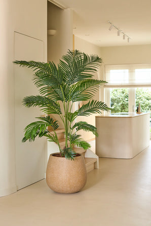 Een Kunstplant Chamaedorea van 180 cm staat in een moderne, lichte keuken met neutrale tinten, een minimalistische inrichting en natuurlijk licht dat door de ramen naar binnen stroomt.