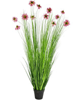 De Kunst Grasplant Chrysant 180 cm brandvertragend is een kunstplant in pot met hoge, dunne groene grasachtige bladeren en roze chrysantbloesems op lange stelen, afgebeeld tegen een witte achtergrond.