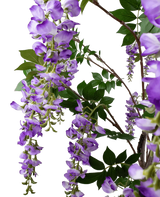 De Kunstplant Blauweregen 210 cm heeft trossen paarse blauweregenbloemen die aan dunne takken met groene bladeren hangen, tegen een effen witte achtergrond.