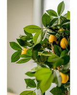 Een close-up van de Kunstplant citroenboom 75 cm, met weelderige groene bladeren en levendige gele citroenen, binnen geplaatst in elegante sierpotten met zacht natuurlijk licht op de achtergrond.